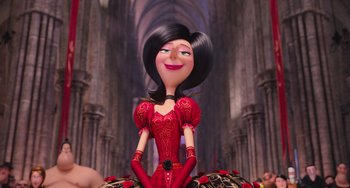 Movie still from “Minions” (2015), directed by Pierre Coffin – A woman in a red dress sitting on a table; Medium shot, Low angle