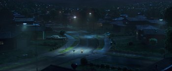 Movie still from “Minions: The Rise of Gru” (2022), directed by Jonathan del Val – A night time view of a street with lights on; Extreme Wide shot, High angle