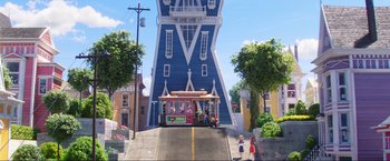 Movie still from “Minions: The Rise of Gru” (2022), directed by Jonathan del Val – A street scene with a trolley going down the street; Extreme Wide shot, Low angle