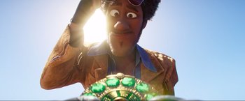 Movie still from “Minions: The Rise of Gru” (2022), directed by Jonathan del Val – A man with a beard and sunglasses is looking at the camera; Close Up shot, Over the shoulder angle