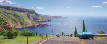 Movie still from “Minions: The Rise of Gru” (2022), directed by Jonathan del Val – A car driving down a road next to a body of water; Extreme Wide shot, Low angle