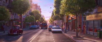 Movie still from “Minions: The Rise of Gru” (2022), directed by Jonathan del Val – A street scene with cars parked on the side of the road; Extreme Wide shot, Low angle