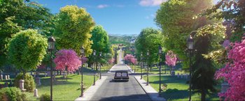 Movie still from “Minions: The Rise of Gru” (2022), directed by Jonathan del Val – A car driving down a street lined with trees; Extreme Wide shot, High angle