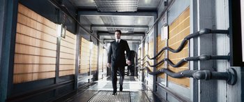 Movie still from “Minority Report” (2002), directed by Steven Spielberg – A man in a suit and tie walking down a hall way; Wide shot, Low angle