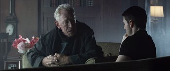 Movie still from “Minority Report” (2002), directed by Steven Spielberg – An older man sitting on a couch looking at a book; Close Up shot, Over the shoulder angle