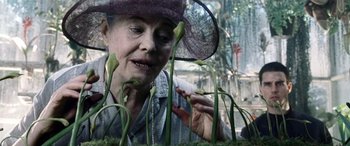Movie still from “Minority Report” (2002), directed by Steven Spielberg – An older woman wearing a purple hat looking at a plant; Close Up shot, Low angle