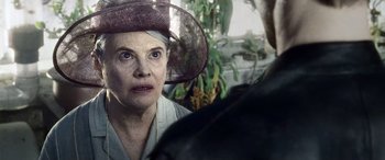 Movie still from “Minority Report” (2002), directed by Steven Spielberg – An older woman wearing a hat looking at a man; Close Up shot, Over the shoulder angle