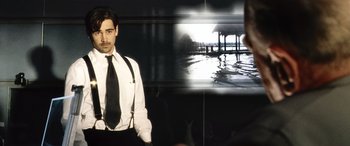 Movie still from “Minority Report” (2002), directed by Steven Spielberg – A man in a suit and tie standing in front of an image of a pier; Medium shot, Over the shoulder angle