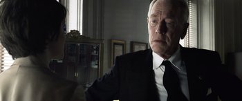 Movie still from “Minority Report” (2002), directed by Steven Spielberg – An older man wearing a suit and tie in a room; Close Up shot, Low angle