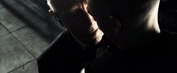 Movie still from “Minority Report” (2002), directed by Steven Spielberg – An older man wearing a suit and tie in the dark; Close Up shot, Over the shoulder angle