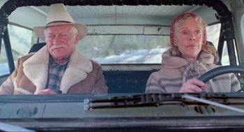 Movie still from “Misery” (1990), directed by Rob Reiner – An older man and woman sitting in the back seat of a car; Medium shot, Low angle