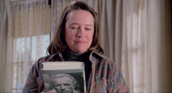 Movie still from “Misery” (1990), directed by Rob Reiner – A woman is holding a book and looking at it; Close Up shot, High angle