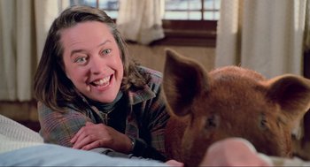 Movie still from “Misery” (1990), directed by Rob Reiner – A woman smiling next to a pig on a bed; Close Up shot, Low angle