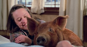 Movie still from “Misery” (1990), directed by Rob Reiner – A woman smiles next to a brown piglet; Close Up shot, High angle