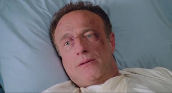 Movie still from “Misery” (1990), directed by Rob Reiner – A person laying in a hospital bed with bruises; Close Up shot, High angle
