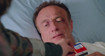 Movie still from “Misery” (1990), directed by Rob Reiner – A man laying in a bed with a bandage on his face; Close Up shot, High angle