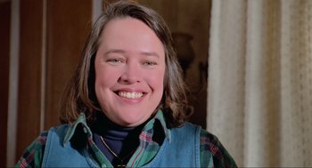 Movie still from “Misery” (1990), directed by Rob Reiner – A person smiling for the camera; Close Up shot, Low angle