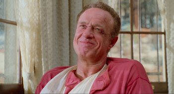 Movie still from “Misery” (1990), directed by Rob Reiner – An older man wearing a pink shirt and white shirt; Close Up shot, Low angle