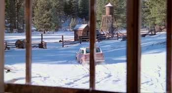 Movie still from “Misery” (1990), directed by Rob Reiner – A truck driving through a snow covered field near a water tower; Extreme Wide shot, High angle
