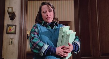Movie still from “Misery” (1990), directed by Rob Reiner – A woman holding a stack of boxes in her hands; Medium shot, Low angle