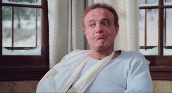 Movie still from “Misery” (1990), directed by Rob Reiner – A man with a bandage on his arm is sitting in a chair; Close Up shot, Low angle