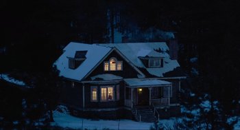 Movie still from “Misery” (1990), directed by Rob Reiner – A house in the snow at night lit by a window; Extreme Wide shot, Low angle