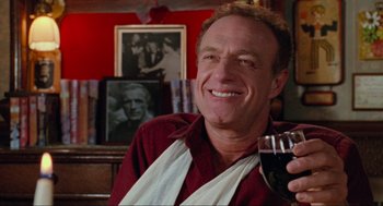 Movie still from “Misery” (1990), directed by Rob Reiner – A man holding a wine glass in his right hand; Close Up shot, Low angle