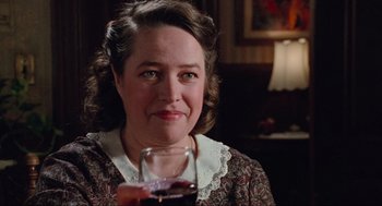 Movie still from “Misery” (1990), directed by Rob Reiner – A woman sitting in front of a glass of wine; Close Up shot, Over the shoulder angle