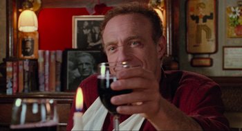 Movie still from “Misery” (1990), directed by Rob Reiner – A man holding a glass of red wine in his right hand; Close Up shot, Low angle