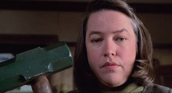 Movie still from “Misery” (1990), directed by Rob Reiner – A person holding a hammer; Close Up shot, Low angle