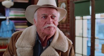 Movie still from “Misery” (1990), directed by Rob Reiner – An older man wearing a white hat and a fur coat; Close Up shot, Low angle