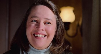 Movie still from “Misery” (1990), directed by Rob Reiner – A person smiling for the camera; Close Up shot, Low angle