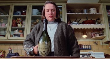 Movie still from “Misery” (1990), directed by Rob Reiner – A woman holding a bottle of champagne in a kitchen; Close Up shot, Low angle