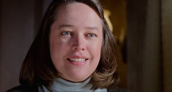 Movie still from “Misery” (1990), directed by Rob Reiner – A woman smiling for the camera; Close Up shot, Low angle