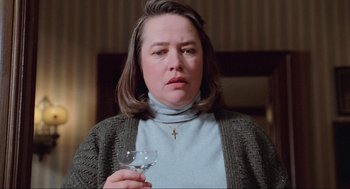 Movie still from “Misery” (1990), directed by Rob Reiner – A woman holding a wine goblet in her hand; Close Up shot, Low angle