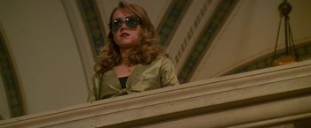 Movie still from “Mission: Impossible” (1996), directed by Brian De Palma – A woman wearing sunglasses standing on top of a stage; Medium shot, Low angle