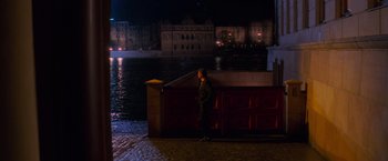 Movie still from “Mission: Impossible” (1996), directed by Brian De Palma – A man standing next to a wall near a body of water at night; Extreme Wide shot, High angle