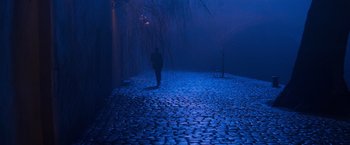 Movie still from “Mission: Impossible” (1996), directed by Brian De Palma – A person is walking on a cobblestone path in the dark; Wide shot, High angle