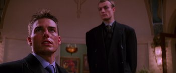Movie still from “Mission: Impossible” (1996), directed by Brian De Palma – Two men in suits and ties standing next to each other in a room; Close Up shot, Low angle