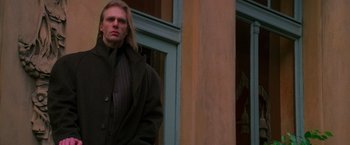 Movie still from “Mission: Impossible” (1996), directed by Brian De Palma – A man standing in front of a building with his head turned to the side; Medium shot, Low angle