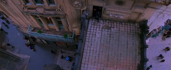 Movie still from “Mission: Impossible” (1996), directed by Brian De Palma – An aerial view of a street with a person walking on the sidewalk; Extreme Wide shot, Overhead angle
