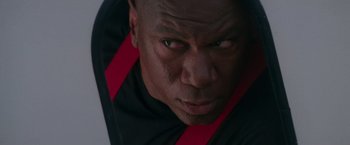 Movie still from “Mission: Impossible” (1996), directed by Brian De Palma – A man's face in a black and red shirt; Close Up shot, Low angle