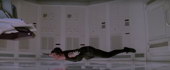 Movie still from “Mission: Impossible” (1996), directed by Brian De Palma – A man in a black suit is laying on the ground; Wide shot, Overhead angle