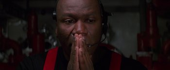 Movie still from “Mission: Impossible” (1996), directed by Brian De Palma – A man in a red shirt is praying; Close Up shot, Low angle