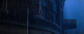 Movie still from “Mission: Impossible” (1996), directed by Brian De Palma – A person sitting on a window ledge in the rain; Extreme Wide shot, Low angle