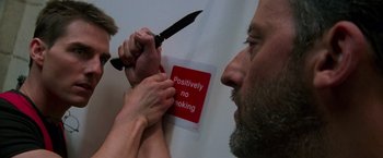 Movie still from “Mission: Impossible” (1996), directed by Brian De Palma – A person cutting a sign with a knife; Close Up shot, Low angle