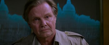 Movie still from “Mission: Impossible” (1996), directed by Brian De Palma – An older man in a tan jacket stares at the camera; Close Up shot, Low angle