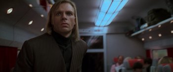 Movie still from “Mission: Impossible” (1996), directed by Brian De Palma – A man with long blonde hair standing in front of a window; Close Up shot, Low angle