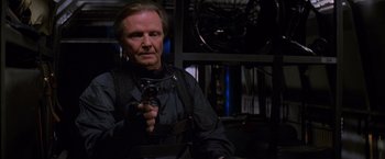 Movie still from “Mission: Impossible” (1996), directed by Brian De Palma – An older man holding a gun in a room; Medium shot, Low angle