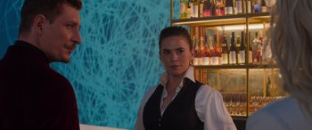 Movie still from “Mission: Impossible - Dead Reckoning Part One” (2023), directed by Christopher McQuarrie – A woman standing in front of a bar with bottles; Medium shot, Over the shoulder angle